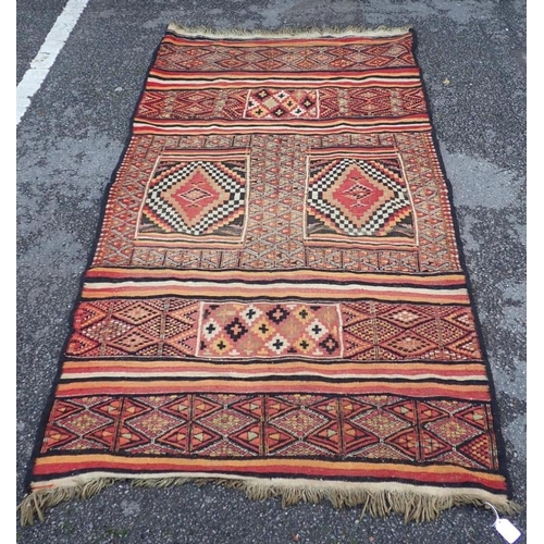 881 - A FLAT-WEAVE RUG, PURCHASED IN THE CAMEROONS in reds, orange green and black, cotton backed with rin... 