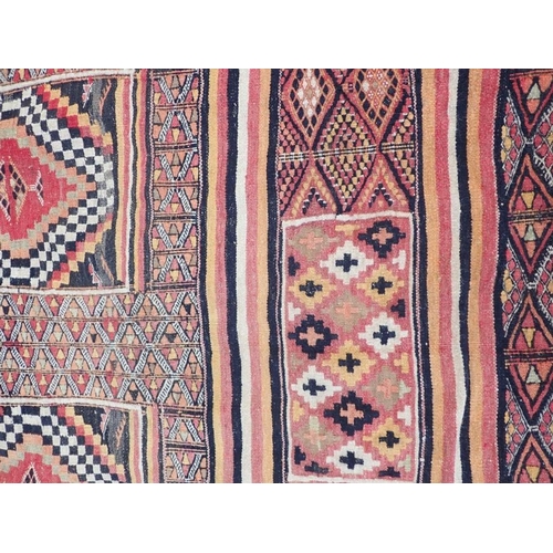 881 - A FLAT-WEAVE RUG, PURCHASED IN THE CAMEROONS in reds, orange green and black, cotton backed with rin... 