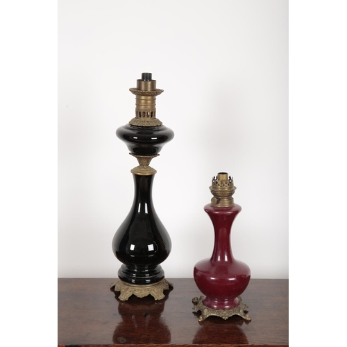 203 - TWO SIMILAR GILT METAL MOUNTED CONVERTED OIL LAMPS the larger with a turned reservoir over a baluste... 