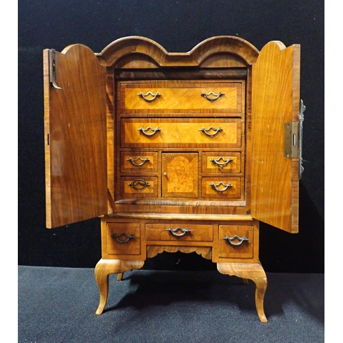 224 - A QUEEN ANNE STYLE WALNUT MINIATURE CHEST ON STAND with two doors opening onto a fully fitted interi... 