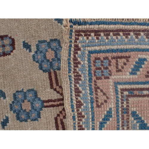 742 - A USHAK RUG woven in blue and brown with endless floral repeat on a mushroom ground, 174 x 96cm (wea... 