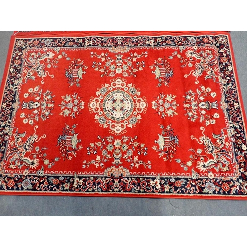 745 - TWO SIMILAR RED GROUND MACHINE MADE RUGS 119 x 169cm, and another smaller rug 85 x 85cm plus fringes... 