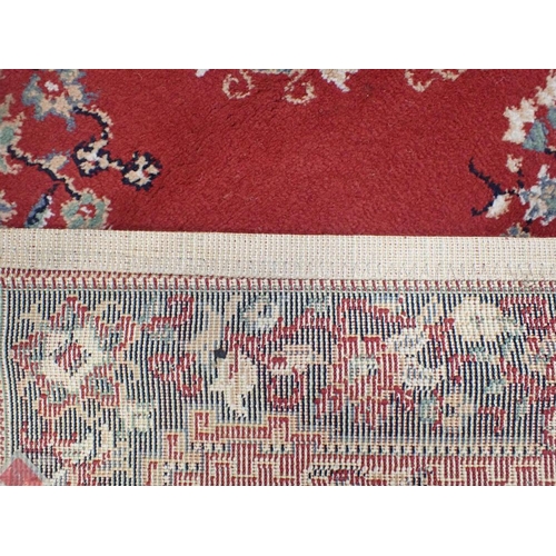 745 - TWO SIMILAR RED GROUND MACHINE MADE RUGS 119 x 169cm, and another smaller rug 85 x 85cm plus fringes... 