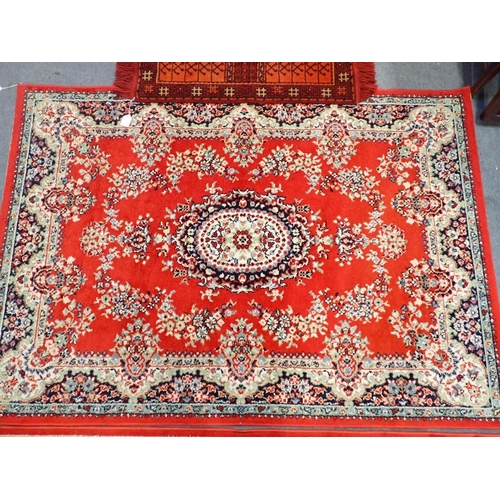 745 - TWO SIMILAR RED GROUND MACHINE MADE RUGS 119 x 169cm, and another smaller rug 85 x 85cm plus fringes... 