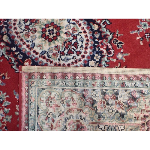 745 - TWO SIMILAR RED GROUND MACHINE MADE RUGS 119 x 169cm, and another smaller rug 85 x 85cm plus fringes... 