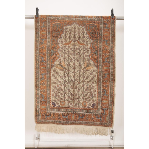 142 - A TURKISH PRAYER RUG

woven in muted colours and orange with birds and trees on a cream ground, with... 