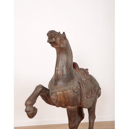 194 - A LARGE CARVED AND PAINTED WOODEN 'TANG' HORSE

posed with one hoof raised and head erect, decked in... 