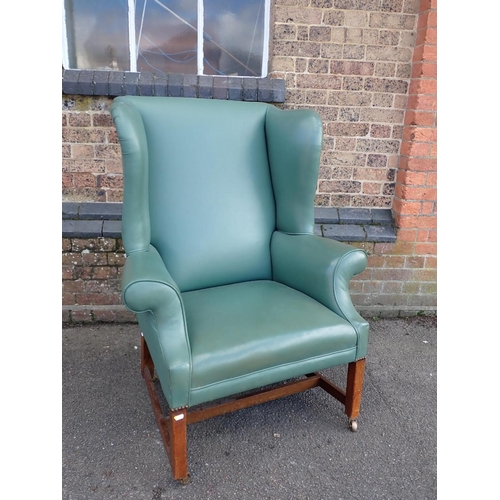 841 - A GEORGE III STYLE WING-BACK ARMCHAIR with square legs, 'H' stretcher and brass castors 90cm wide