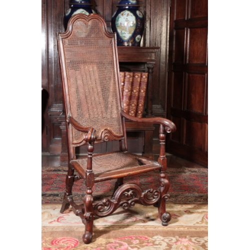 15 - A WILLIAM AND MARY WALNUT AND STAINED WOOD ELBOW CHAIR

with a caned back and seat, the 