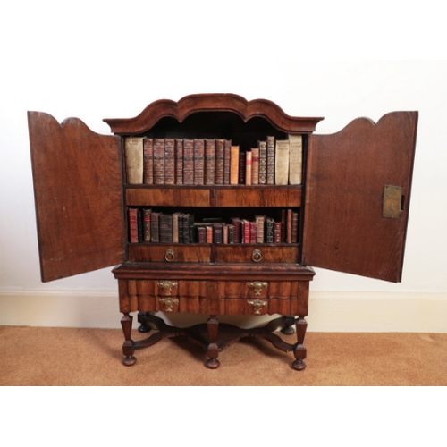 167 - A DUTCH MINIATURE WALNUT CABINET ON STAND

with a shaped cornice over a pair of panelled doors enclo... 