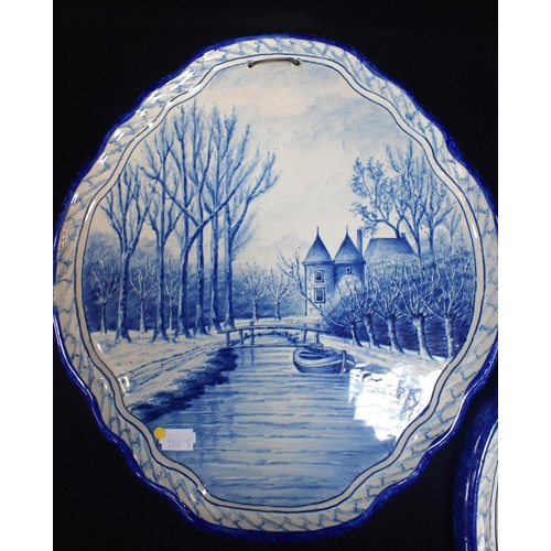 14 - A PAIR OF DELFT STYLE BLUE AND WHITE PLAQUES of cartouche form, decorated with canal scenes within m... 