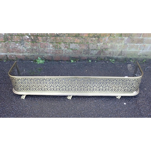 164 - A PIERCED BRASS FENDER, ON PAW FEET 23cm high, 122cm wide, with a tubular brass magazine rack (a/f) ... 