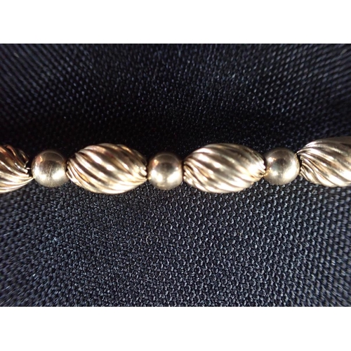 492 - A GOLD FILLED STYLISED BRACELET comprising a series of whorled fluted beads