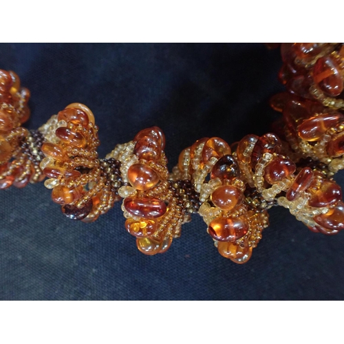 525 - AN AMBER BEAD NECKLACE the beads set in a wide spiral form, on a meshed base