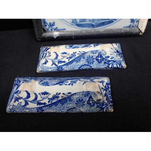 392 - A PAIR OF EARLY 19TH CENTURY BLUE AND WHITE KNIFE RESTS and a framed Delft tile, painted with a chur... 