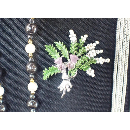 508 - A GEMSET THISTLE AND HEATHER BROOCH with a white metal multi-chain necklace and a black and white fa... 