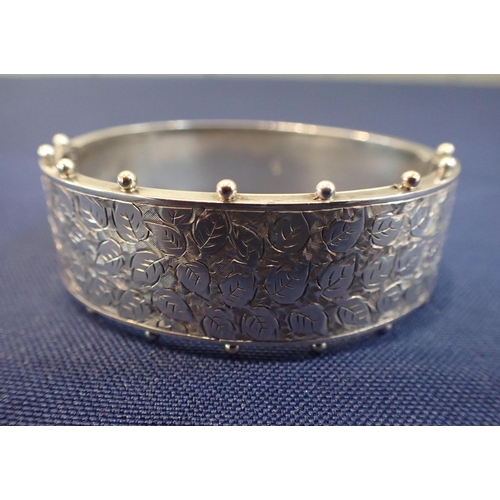 529 - A VICTORIAN BANGLE AND BROOCH in sterling silver, the hinged bangle engraved to the top with leaves,... 