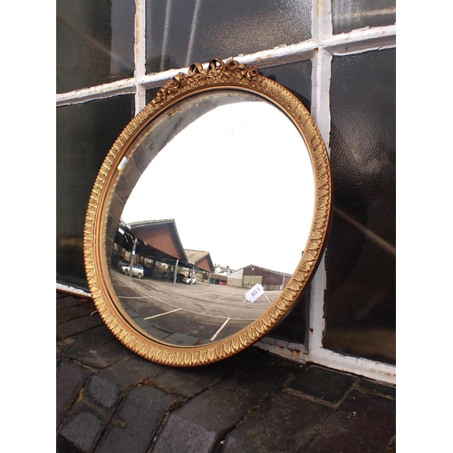 806 - A GILT-FRAMED CONVEX MIRROR with stiff acanthus and ribbon decoration 45cm dia