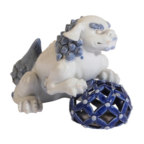 246 - A JAPANESE HIRADO BLUE AND WHITE LION DOG

Meiji period, figured with front feet atop a latticework ... 