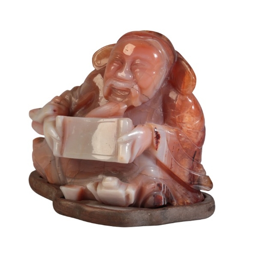 51 - A CHINESE CARVED AGATE FIGURE OF A RECLINING SCRIBE

20th century, 8cm high x 9.5cm wide, on a hardw... 