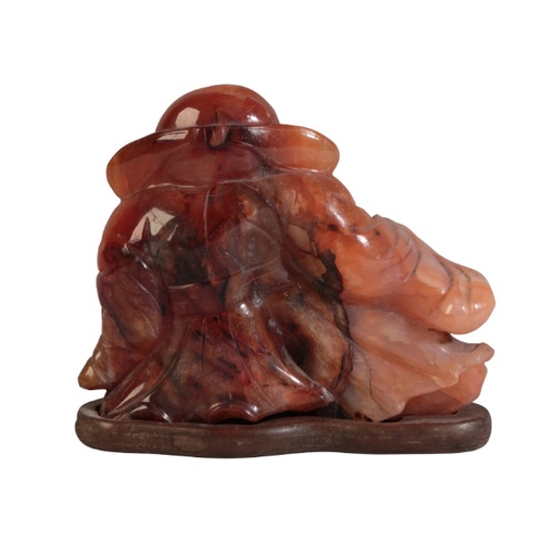 51 - A CHINESE CARVED AGATE FIGURE OF A RECLINING SCRIBE

20th century, 8cm high x 9.5cm wide, on a hardw... 