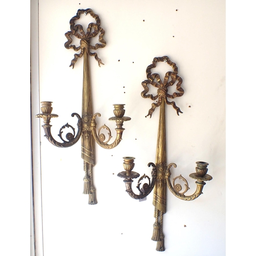 119 - A PAIR OF NEOCLASSICAL STYLE CAST BRASS CANDLE APPLIQUES of tied ribbon design, twin scrolling branc... 