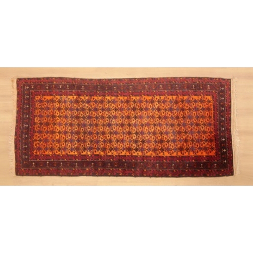 345 - A BELUCH LONG RUG

woven in muted colours with endless floral vase repeat, on an orange ground, with... 