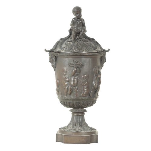 97 - A BRONZE URN AND COVER

early 19th century, with seated cherub finial, the body with twin satyr hand... 