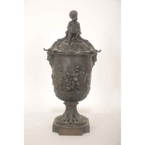 97 - A BRONZE URN AND COVER

early 19th century, with seated cherub finial, the body with twin satyr hand... 