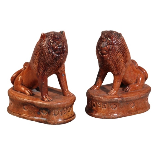 84 - A PAIR OF ENGLISH TREACLE-GLAZED TERRACOTTA LIONS

each impressed 'D 1905 E', probably Staffordshire... 