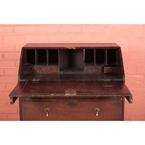 185 - A GEORGE II OAK BUREAU

the two short and two long drawers with pear-drop brass handles on bracket f... 