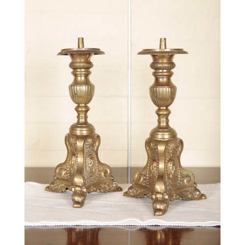 236 - A PAIR OF CONTINENTAL BRASS PRICKET CANDLESTICKS

19th century, on triform bases embossed with masks... 