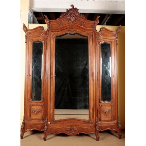 266 - A FRENCH WALNUT TRIPLE WARDROBE

with an ornately carved cornice over three mirrored cupboards, on s... 