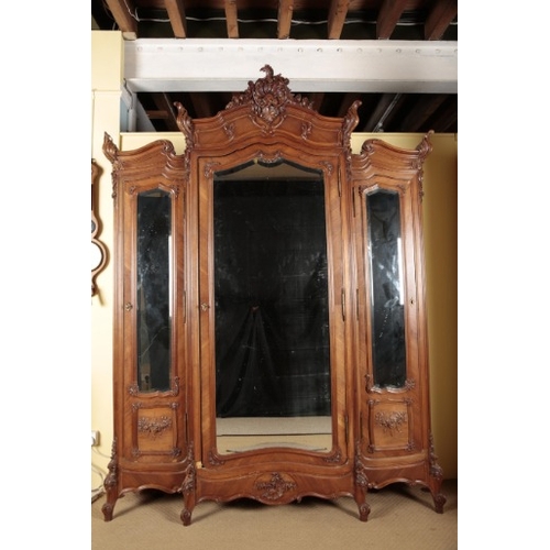 266 - A FRENCH WALNUT TRIPLE WARDROBE

with an ornately carved cornice over three mirrored cupboards, on s... 