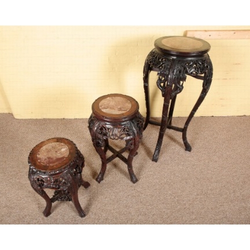 306 - AN ASSOCIATED SET OF THREE CHINESE HARDWOOD JARDINIERE STANDS

each with a marble inset top over a p... 