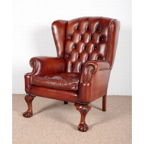 647 - A GEORGIAN STYLE BROWN LEATHER WING BACK CHAIR

on carved shell motif claw and ball feet, 101cm high... 