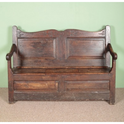 761 - AN OAK SETTLE

early 18th century, the panelled back with a shaped and carved cresting, the seat wit... 