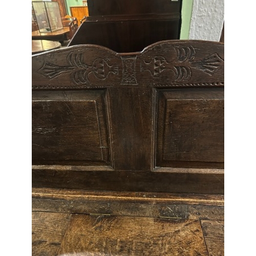 761 - AN OAK SETTLE

early 18th century, the panelled back with a shaped and carved cresting, the seat wit... 