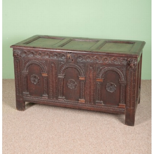 817 - A CARVED OAK CHEST

18th century, with a three panel top, the front with carved decoration of lion m... 