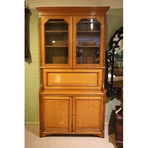 879 - A LATE VICTORIAN GOLDEN OAK SECRETAIRE BOOKCASE

with stepped angled cornice and reeded uprights, fi... 