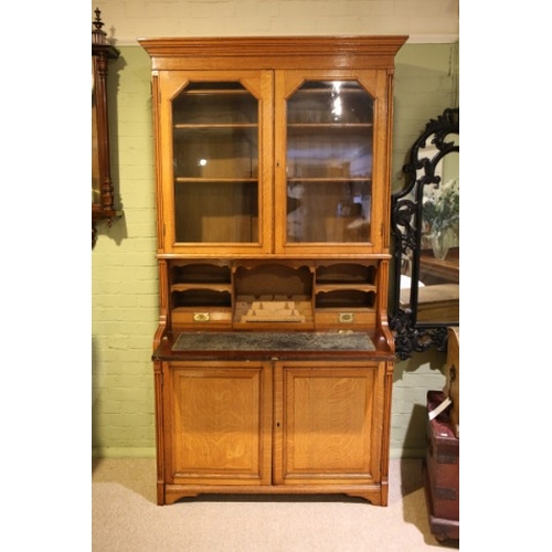 879 - A LATE VICTORIAN GOLDEN OAK SECRETAIRE BOOKCASE

with stepped angled cornice and reeded uprights, fi... 