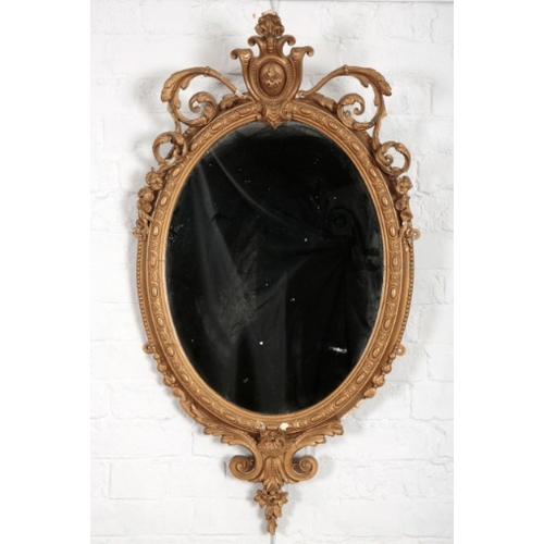 886 - A LATE VICTORIAN GILT GESSO OVAL WALL MIRROR

with scrolled leaf cresting, conforming apron, ovolo b... 