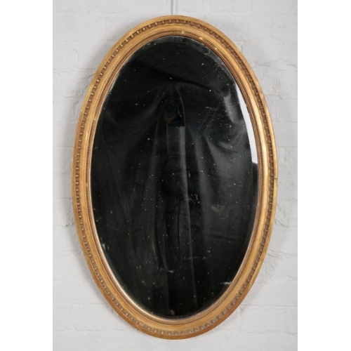 886 - A LATE VICTORIAN GILT GESSO OVAL WALL MIRROR

with scrolled leaf cresting, conforming apron, ovolo b... 