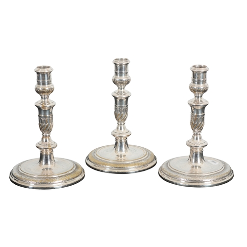 28 - A SET OF THREE 19TH CENTURY SILVER-PLATED CANDLESTICKS

of 18th Century design with leaf capped cyli... 