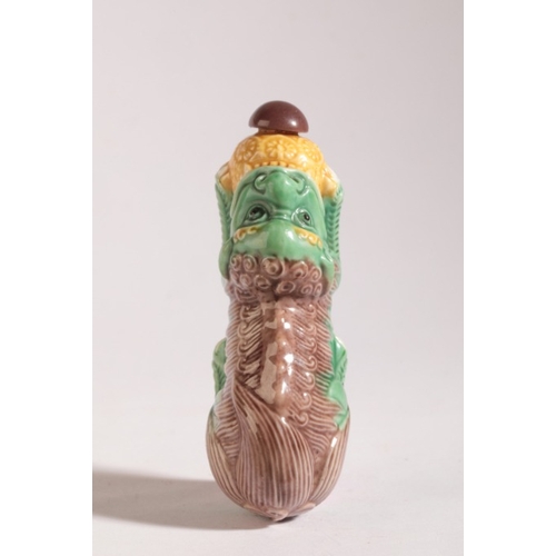 151 - A CHINESE PORCELAIN SNUFF BOTTLE

20th century, in the form of a reclining lion dog, 7.5cm long over... 