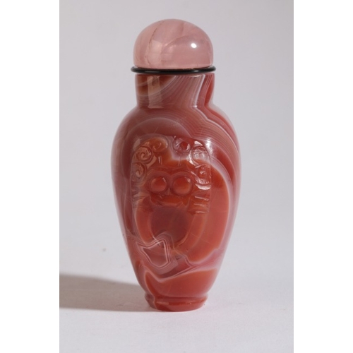 87 - A CHINESE AGATE SNUFF BOTTLE

19th century, with white striations to the red stone, carved mask and ... 