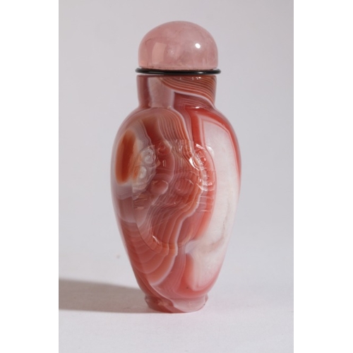 87 - A CHINESE AGATE SNUFF BOTTLE

19th century, with white striations to the red stone, carved mask and ... 