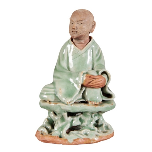 379 - A CHINESE TERRACOTTA AND LONGQUAN CLEADON GLAZED FIGURE

Ming dynasty style, seated on a naturalisti... 