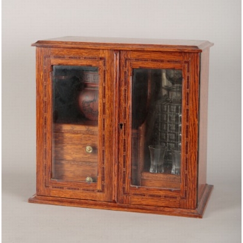 196 - AN OAK SMOKER'S COMPANION

Edwardian, the two glazed doors before shelving to the left-hand side for... 