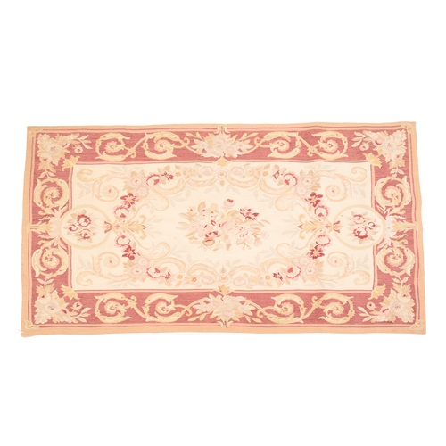 233 - A NEEDLEWORK RUG

woven in colours with central floral spray within floral scroll borders, 153cm x 9... 